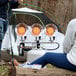 A man and woman sitting on chairs next to a Mr. Heater propane tank top heater.