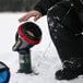 A person in black pants using a Mr. Heater Little Buddy portable radiant heater to warm their feet in an outdoor setting.