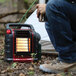 A man sitting next to a Mr. Heater Portable Buddy radiant heater on an outdoor patio.