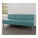 A Lesro Luxe Lounge Series blue vinyl 3-seat sofa with metal legs in a lounge area with a wood floor.