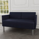 A Lesro navy blue loveseat with steel legs in a lounge area.