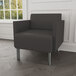 A Lesro Luxe Lounge black vinyl guest chair with steel legs in a lounge area.