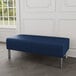 A Lesro blue vinyl bench with steel legs in a lounge area.