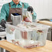 A man using a VacPak-It sous vide circulator to cook meat in a plastic container.