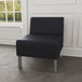 A Lesro Luxe Lounge black vinyl guest chair with steel legs in a lounge area.