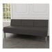 A Lesro Luxe Lounge charcoal vinyl sofa with steel legs in a lounge with wood floors.