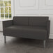 A Lesro Luxe Lounge loveseat with gray vinyl and steel legs in a lounge area.