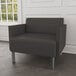 A Lesro Luxe Lounge Series black vinyl bariatric guest arm chair with steel legs in a lounge area.