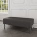 A black Lesro Luxe 2-seat bench with steel legs in a lounge area.