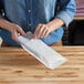 A person holding a white customizable paper layflat shipping bag with a Vela logo.