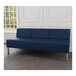 A Lesro Luxe Lounge series blue vinyl sofa with steel legs in a room with a white wall and wood floor.