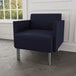 A Lesro navy blue fabric guest chair with steel legs in a lounge area.