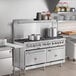 A large stainless steel Cooking Performance Group range with pots on top in a professional kitchen.