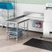 A Regency stainless steel L-shape dishtable on a stainless steel counter in a commercial kitchen.