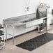 A Regency 3-compartment soiled dish table with a left drainboard over a stainless steel counter in a kitchen.