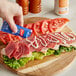 A person putting French's Mayonnaise packet on a sandwich.