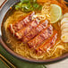 A bowl of ramen with meat and vegetables in a broth with McCormick Culinary Vietnamese Cajun Seasoning.