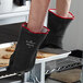 A person wearing Showa black neoprene oven mitts holding a tray of cookies.