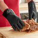 A person in Showa black gloves cutting meat on a cutting board.