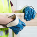 A person wearing blue Cordova Brawler gloves holding a wooden plank.