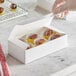 A hand putting chocolate into a white Baker's Lane candy box.