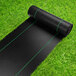 A roll of black material on grass.