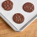 A Baker's Lane parchment paper lined bun pan with chocolate chip cookies.