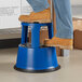 A person standing on a blue Lavex Steel rolling step stool.