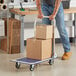 A man pushing a Lavex steel folding platform truck with boxes on it.