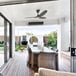 A Big Ass Fans Vesper electric patio heater hanging from a ceiling above a dining table with candles and a potted plant.