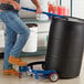 A man using a blue Lavex drum caddy to push a barrel.