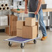A man pushing a Lavex steel platform truck with a stack of cardboard boxes.