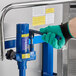 A hand in a green glove holding a blue pipe.