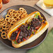 A plate with a sandwich made with PAOW! Plant-Based Beef and vegetables next to pretzels.