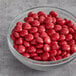 A bowl of Red Milk Chocolate Gems on a counter.