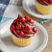 A cupcake with chocolate frosting and red candies on top.