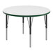 A white round Correll activity table with green T-molded legs.