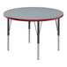A Correll round activity table with a gray top and red legs.