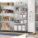 Regency stationary stainless steel shelving with boxes and containers on it in a school kitchen.