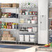 A Regency stainless steel shelving unit in a school kitchen with shelves holding boxes and containers.