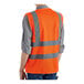 A person wearing a Lavex orange high visibility safety vest with reflective stripes.