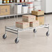 A Regency stainless steel wire cart with boxes on it.