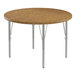 A close-up of a Correll round wooden activity table with silver legs and medium oak T-mold.