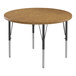 A Correll round activity table with medium oak wooden top and black metal legs.