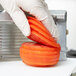 A person in gloves using a Vollrath Redco Tomato Pro to slice a tomato.