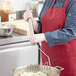 A hand holding a Fourt&#233; stainless steel square-faced potato masher over a bowl of mashed potatoes.