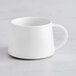 An Acopa Lore bright white porcelain cup with a handle on a white table.