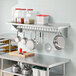 A kitchen with a Regency stainless steel wall-mounted pot rack shelf with pots and pans.