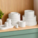 A stack of Acopa Lore bright white raised rim porcelain bowls on a shelf.