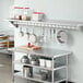 A kitchen with a Regency stainless steel wall-mounted pot rack shelf holding pots.